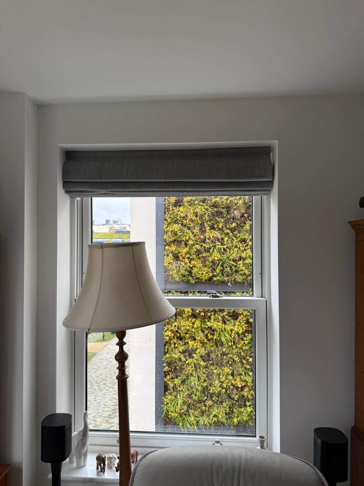 Secondary glazing with vertical slider in living room with floor lamp and garden view