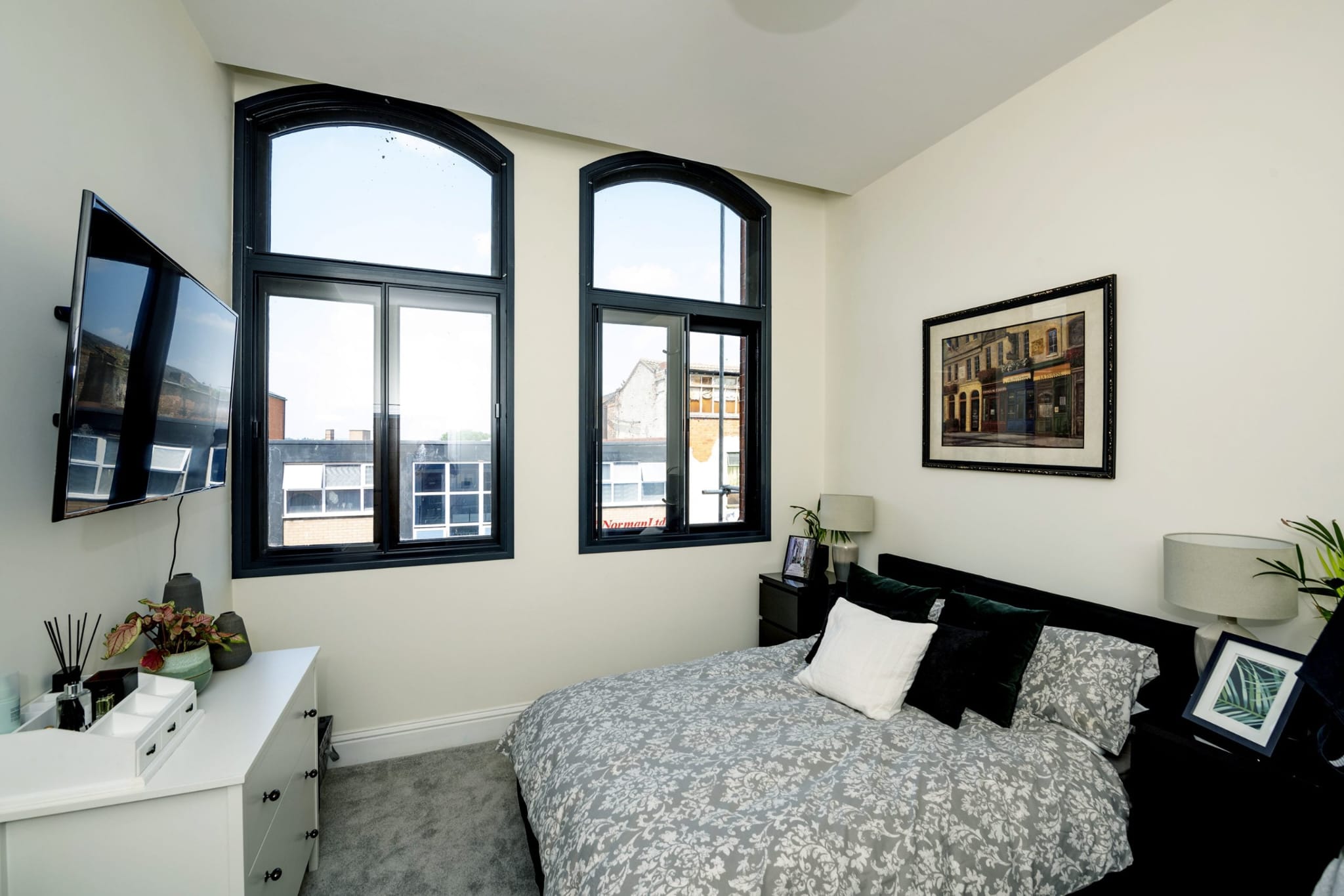 Black arched secondary glazing installed in modern apartment bedroom — dark powder-coated aluminium frame