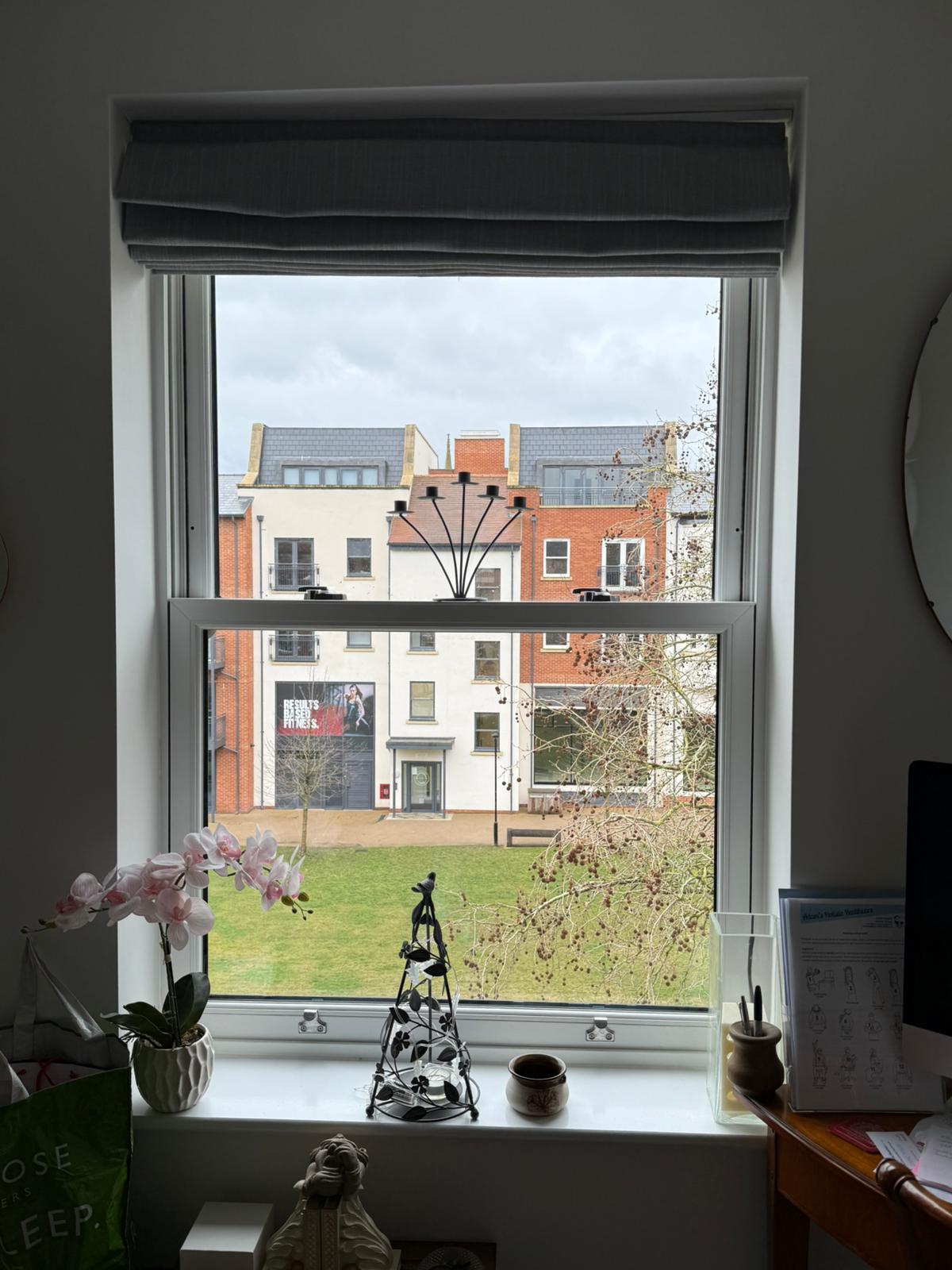 Vertical sliding secondary glazing with white aluminium frame in residential home office setting