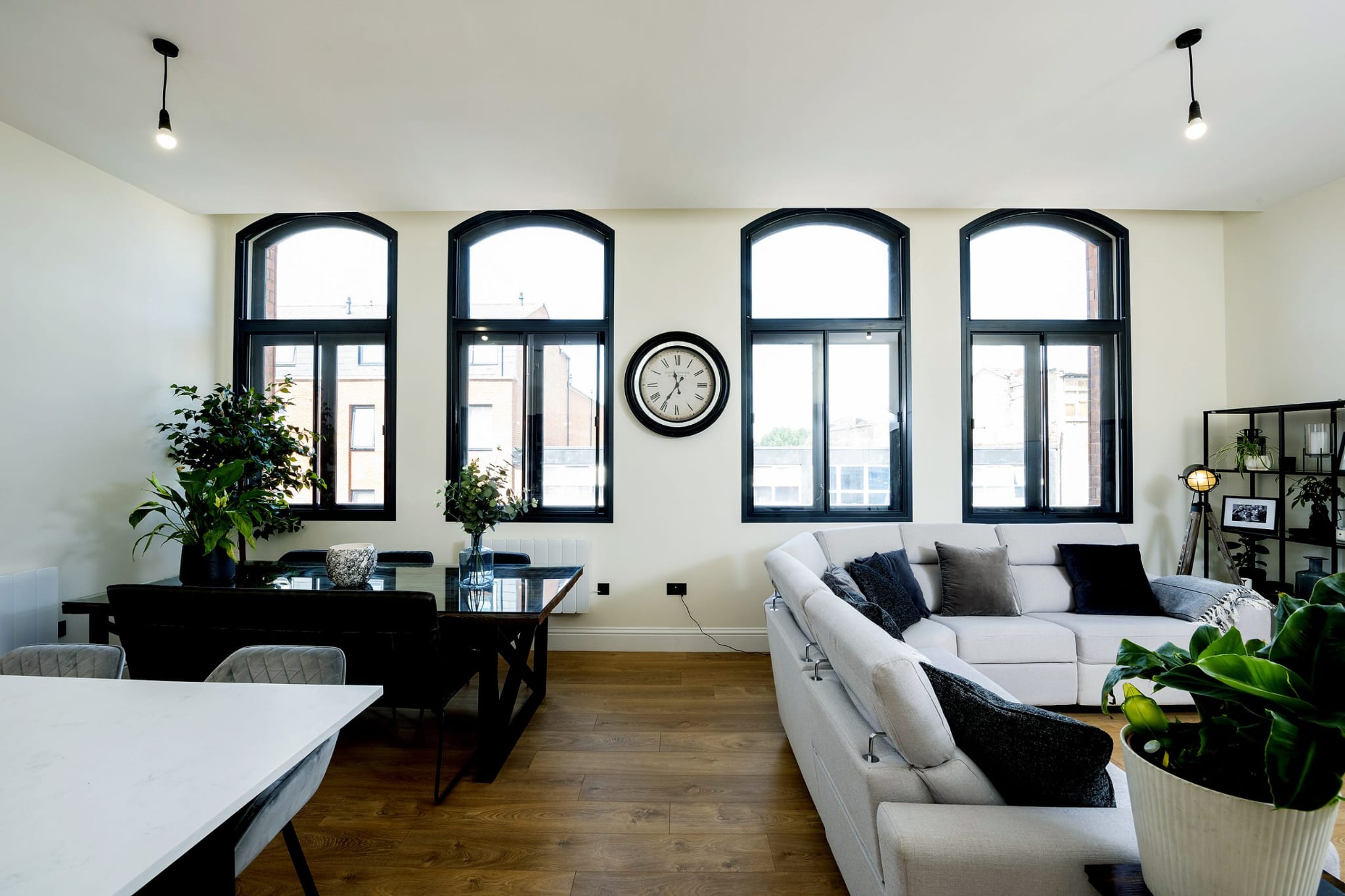Four large black arched secondary glazed windows in open-plan apartment living space — commercial conversion