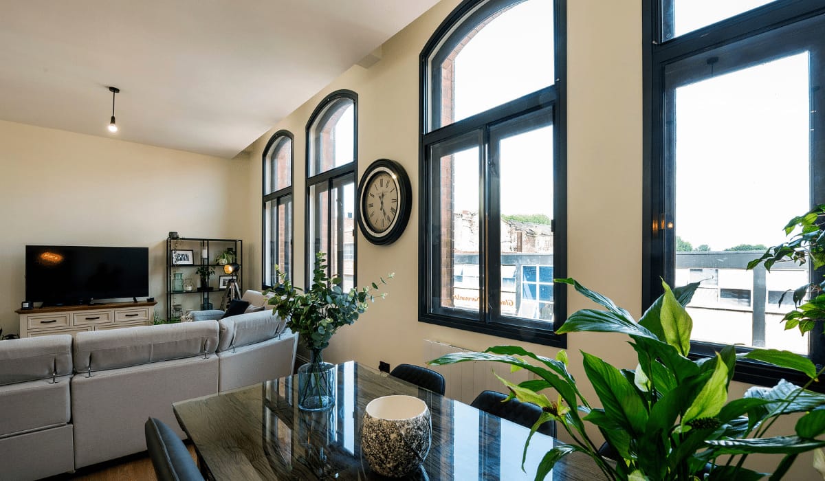 Black arched secondary glazing in open-plan apartment dining and living area — wide angle view
