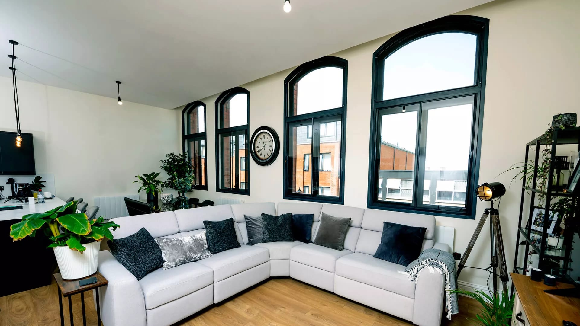 Wide angle view of black arched secondary glazing across full wall of open-plan apartment lounge