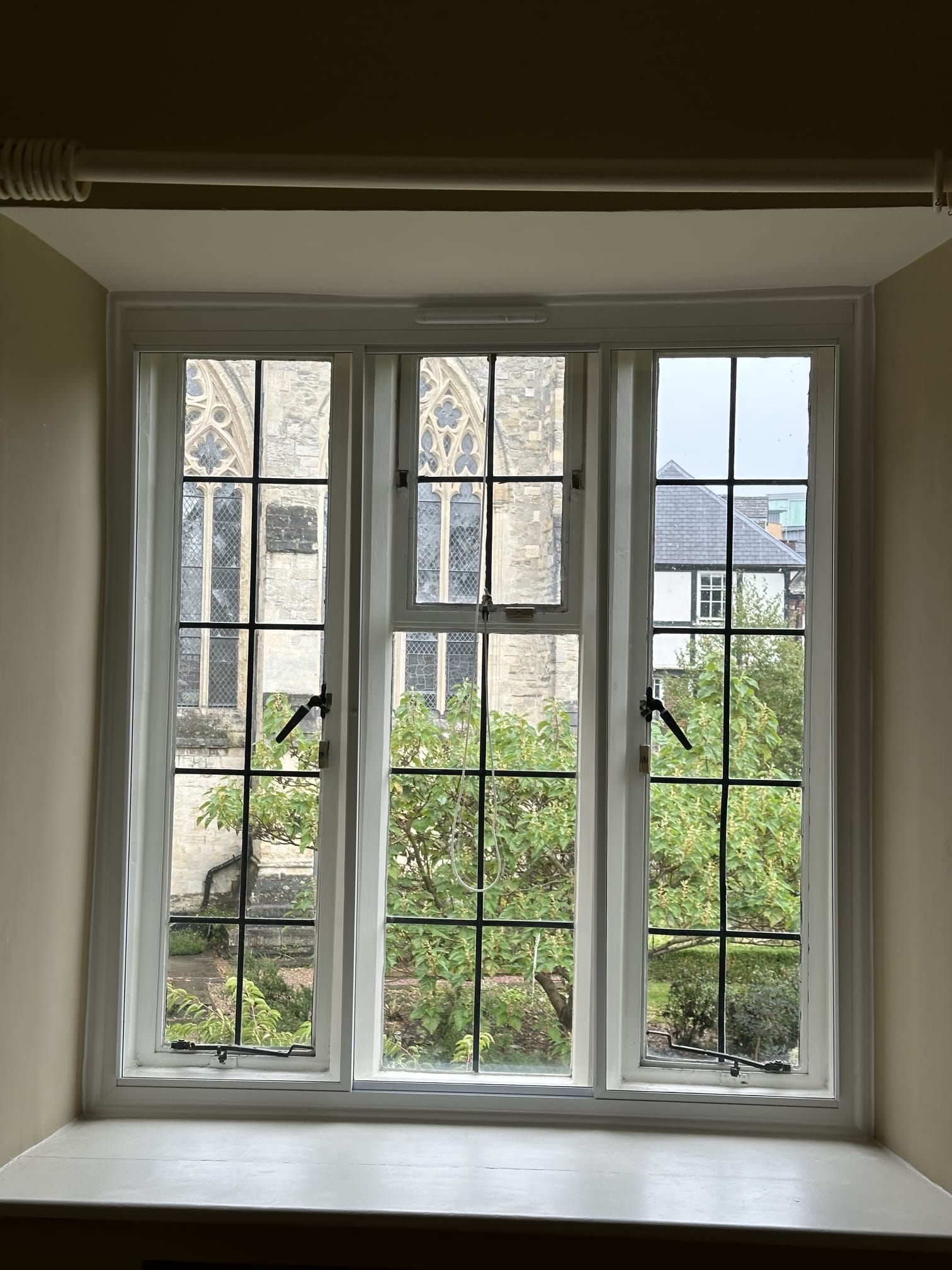 Three-panel secondary glazing on period property window overlooking cathedral stonework and garden