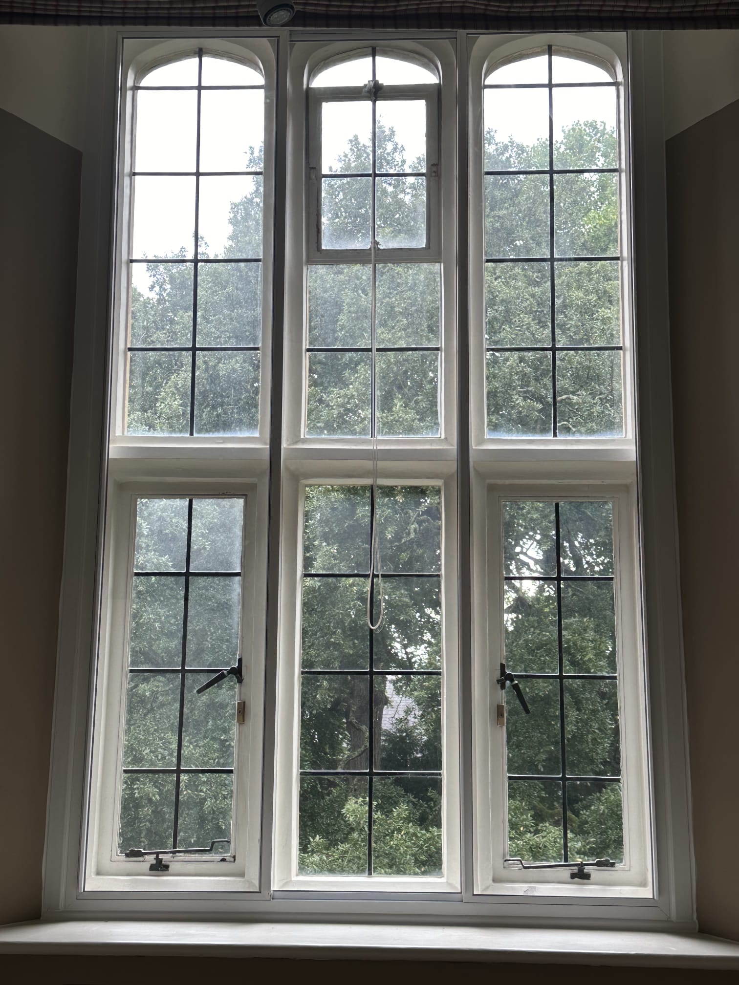 Three tall arched panels with secondary glazing on heritage property surrounded by mature trees