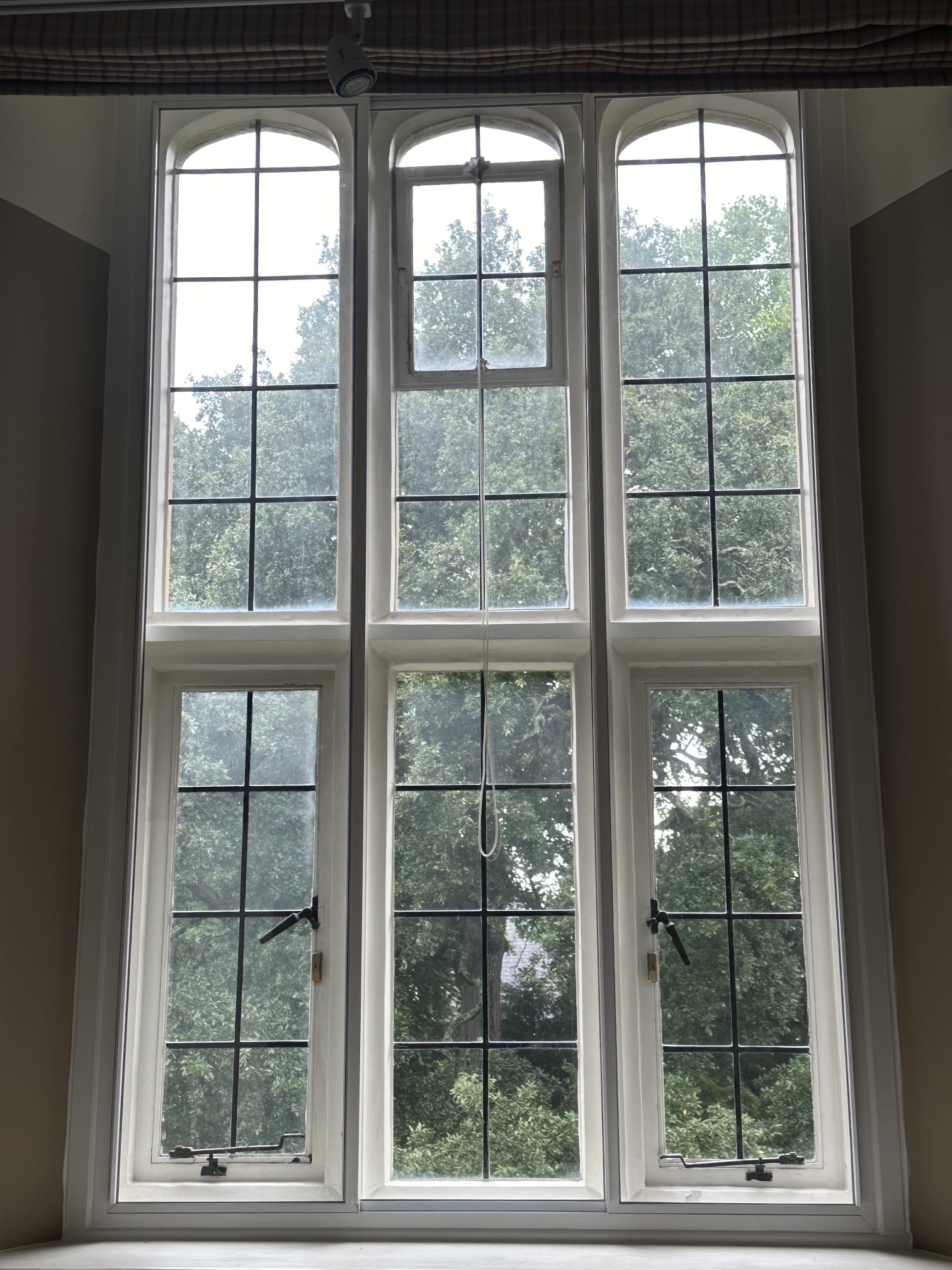 Three-panel white secondary glazing on period property bedroom window overlooking cathedral and colourful garden
