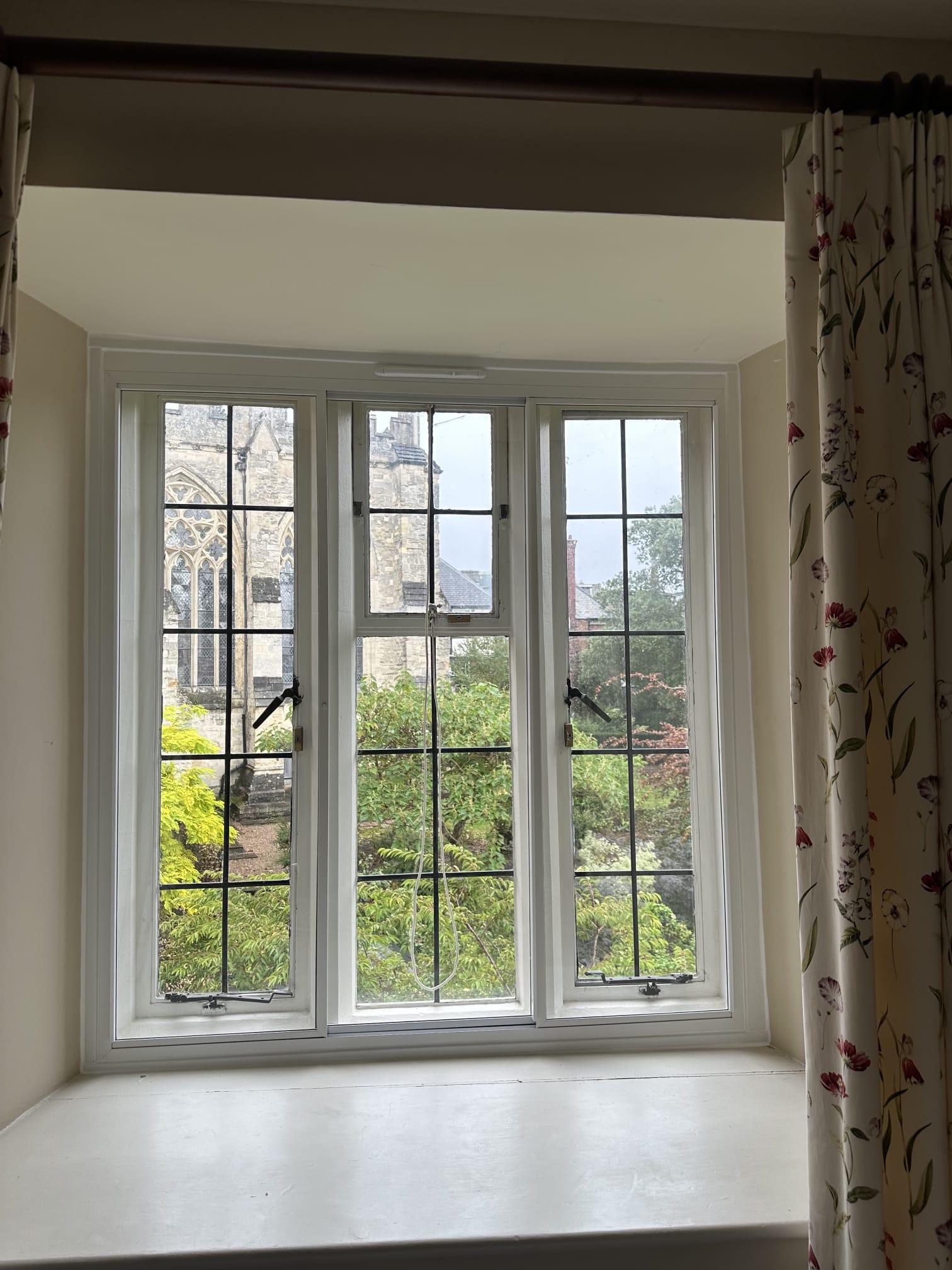 Slim double-panel secondary glazing on tall narrow windows — white aluminium with black espag handles