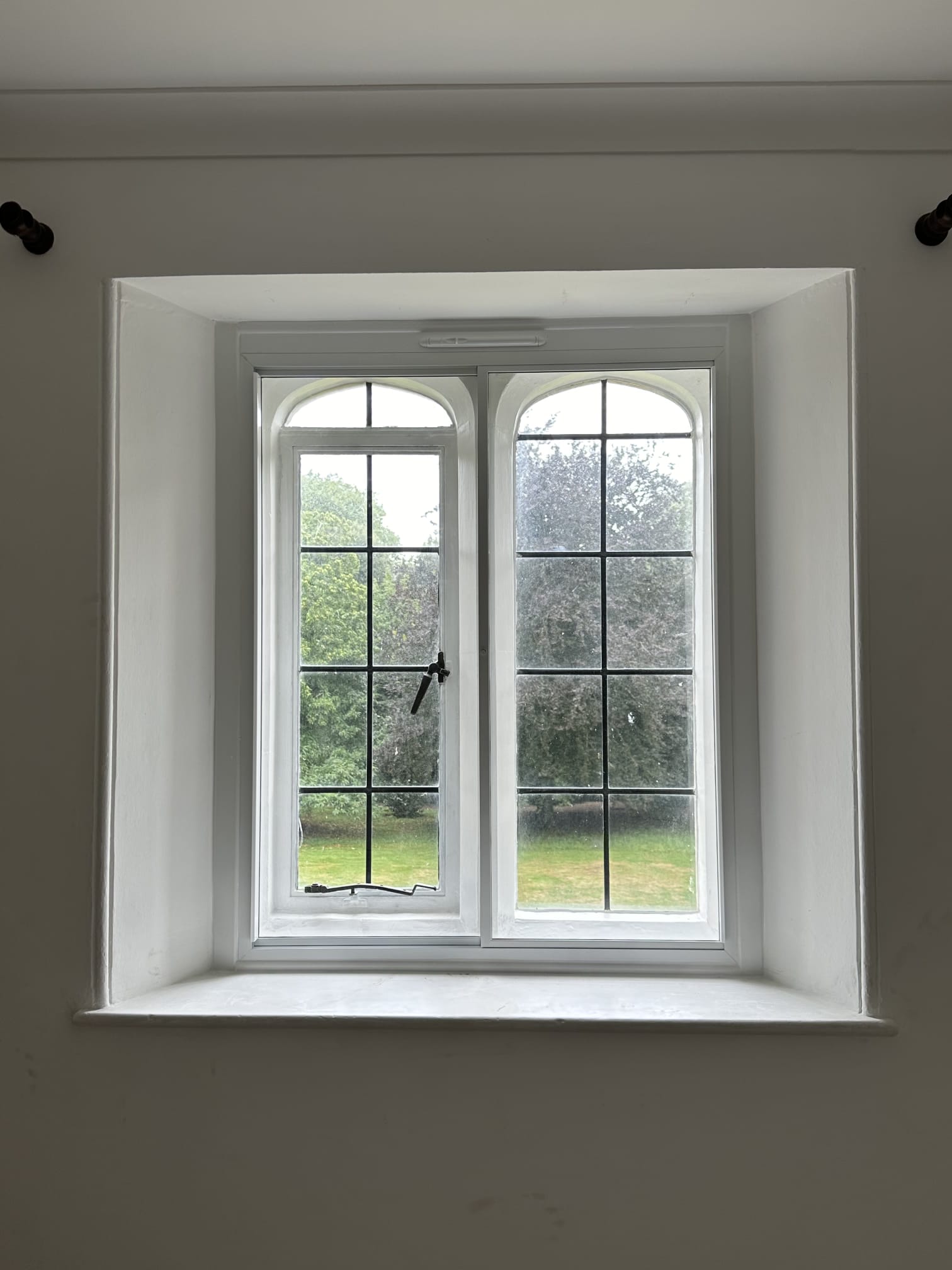 Three-panel vertical sliding secondary glazing on period property with views of Victorian terrace and mature garden