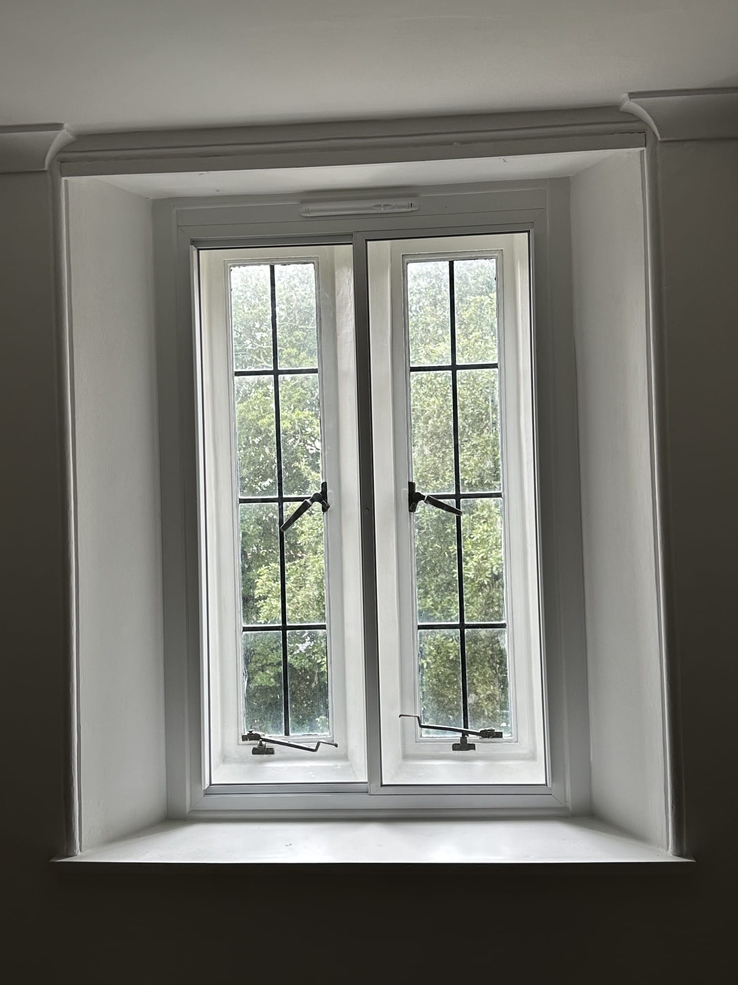 Three vertical sliding secondary glazing panels on period property overlooking autumnal Victorian terrace